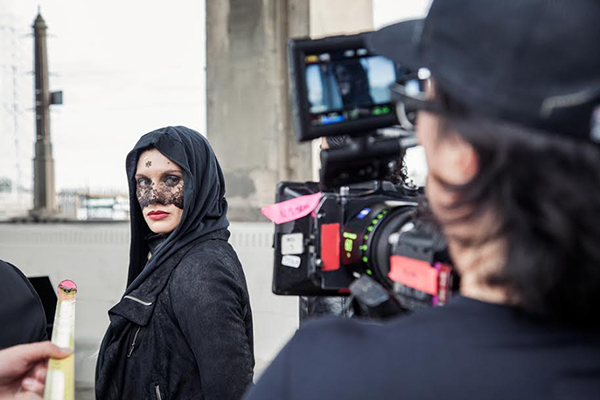 Behind the camera shooting a woman in a black dress for a film